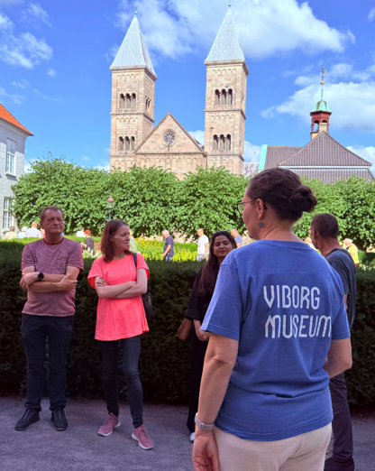 en gruppe på byvandring i latinerhaven med domkirken i baggrunden