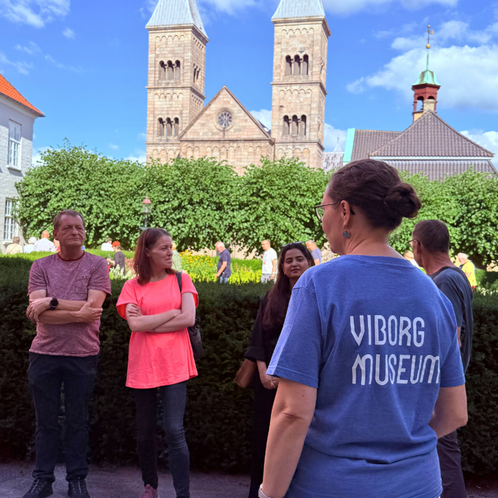 en gruppe på byvandring i latinerhaven med domkirken i baggrunden