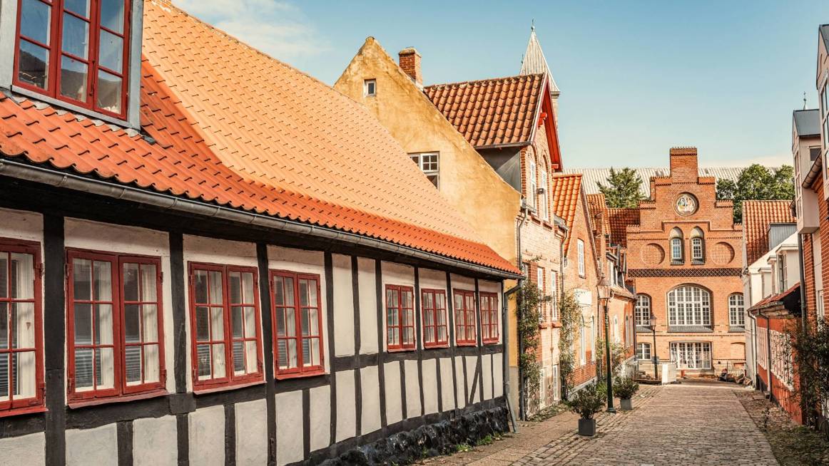 En hyggelig brostensgade i Viborg med et bindingsværkshus badet i aftensol.