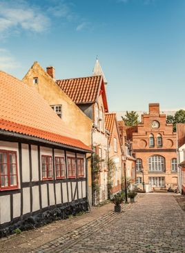 En hyggelig brostensgade i Viborg med et bindingsværkshus badet i aftensol