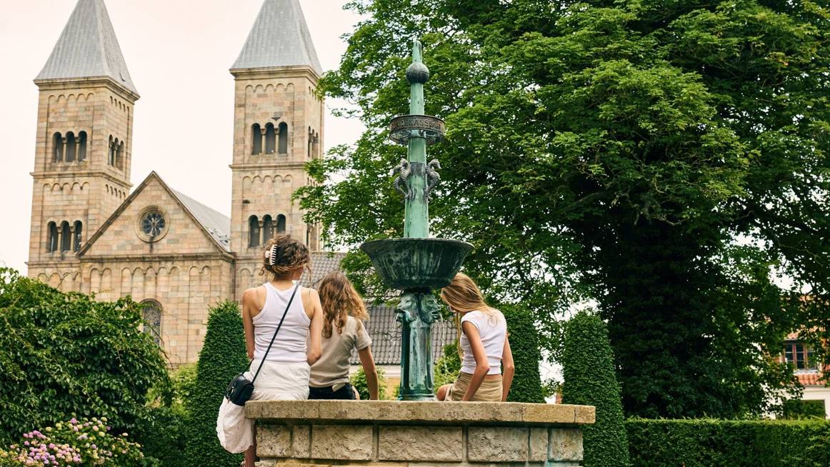Viborg Domkirke set fra Latinerhaven, hvor en familie sidder ved et springvand. foto: Nikolai Frantzen
